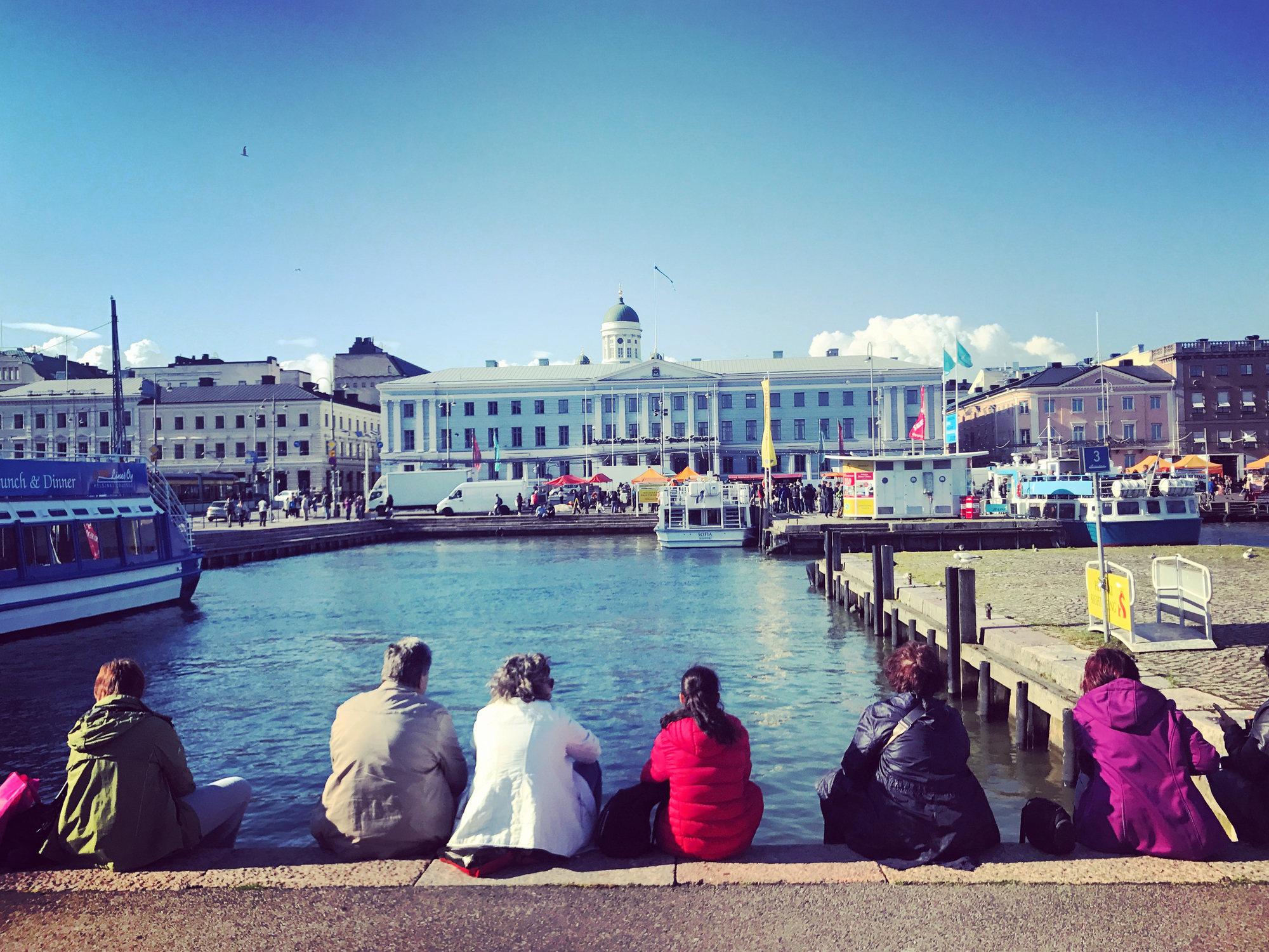 People enjoying beautiful view on Market Square and marina in old Helsinki , Finland