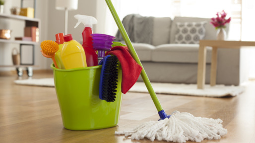 Plastic bucket with cleaning supplies in home