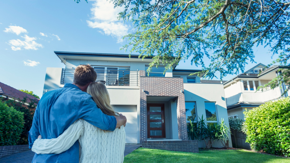 couple-standing-in-front-of-their-new-home-picture-id504224016