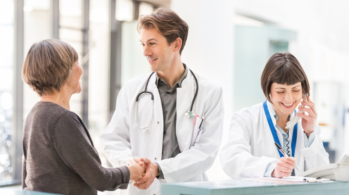 doctors-and-patient-at-reception-desk-picture-id157403538