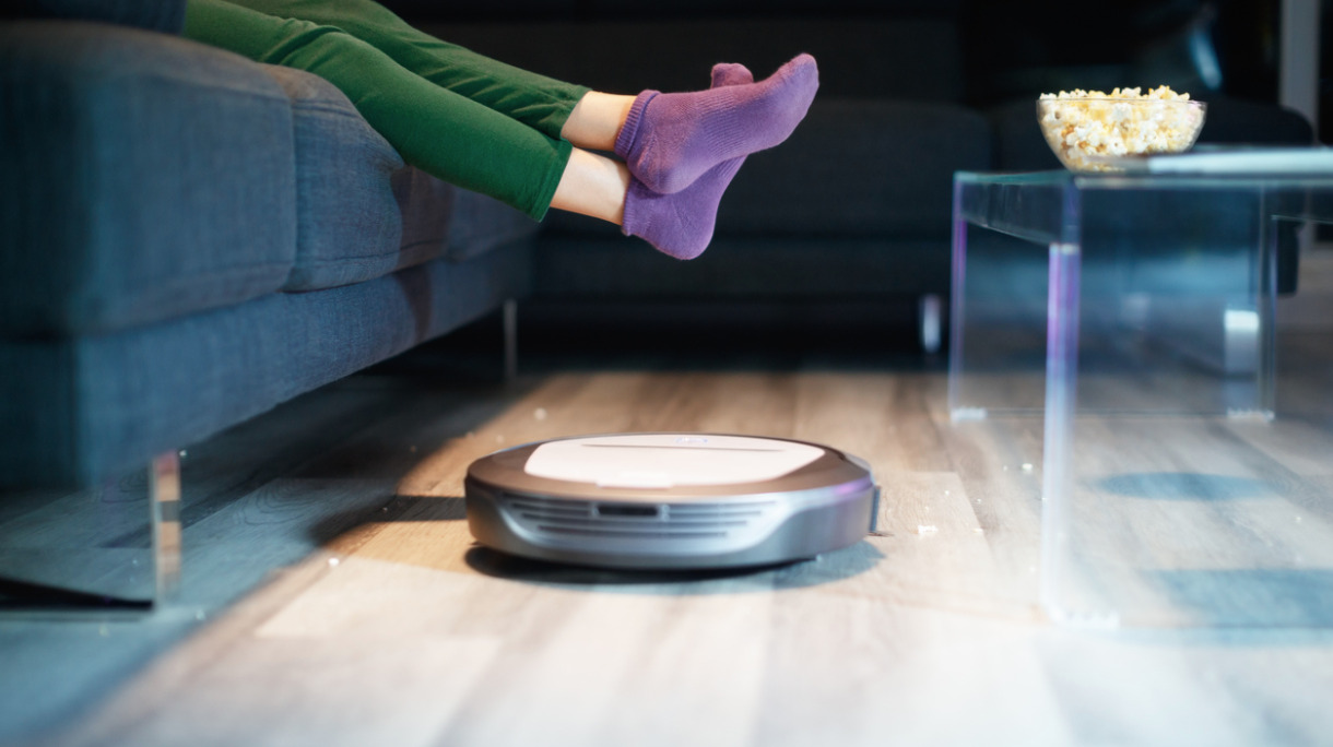 robot-cleaning-floor-while-child-watches-tv-movie-picture-id901992126