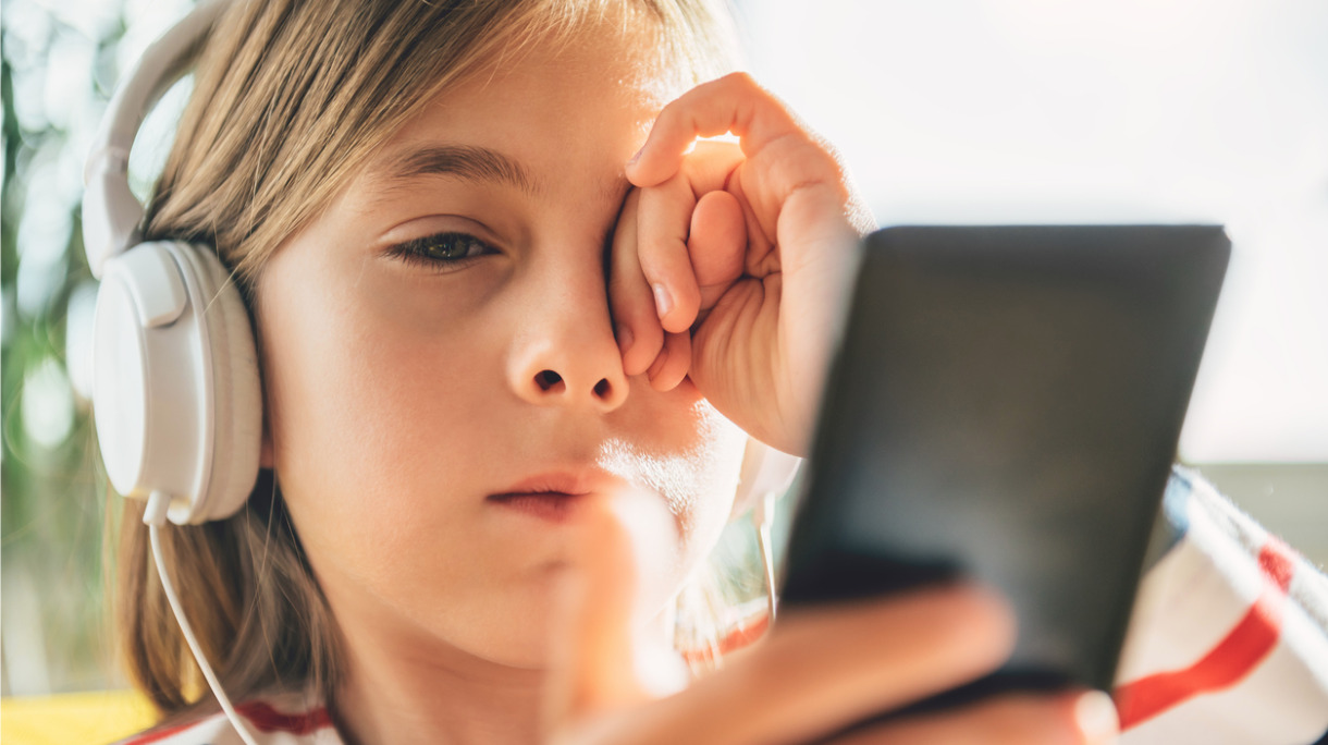 tired-little-girl-with-headphones-using-smart-phone-picture-id869002238