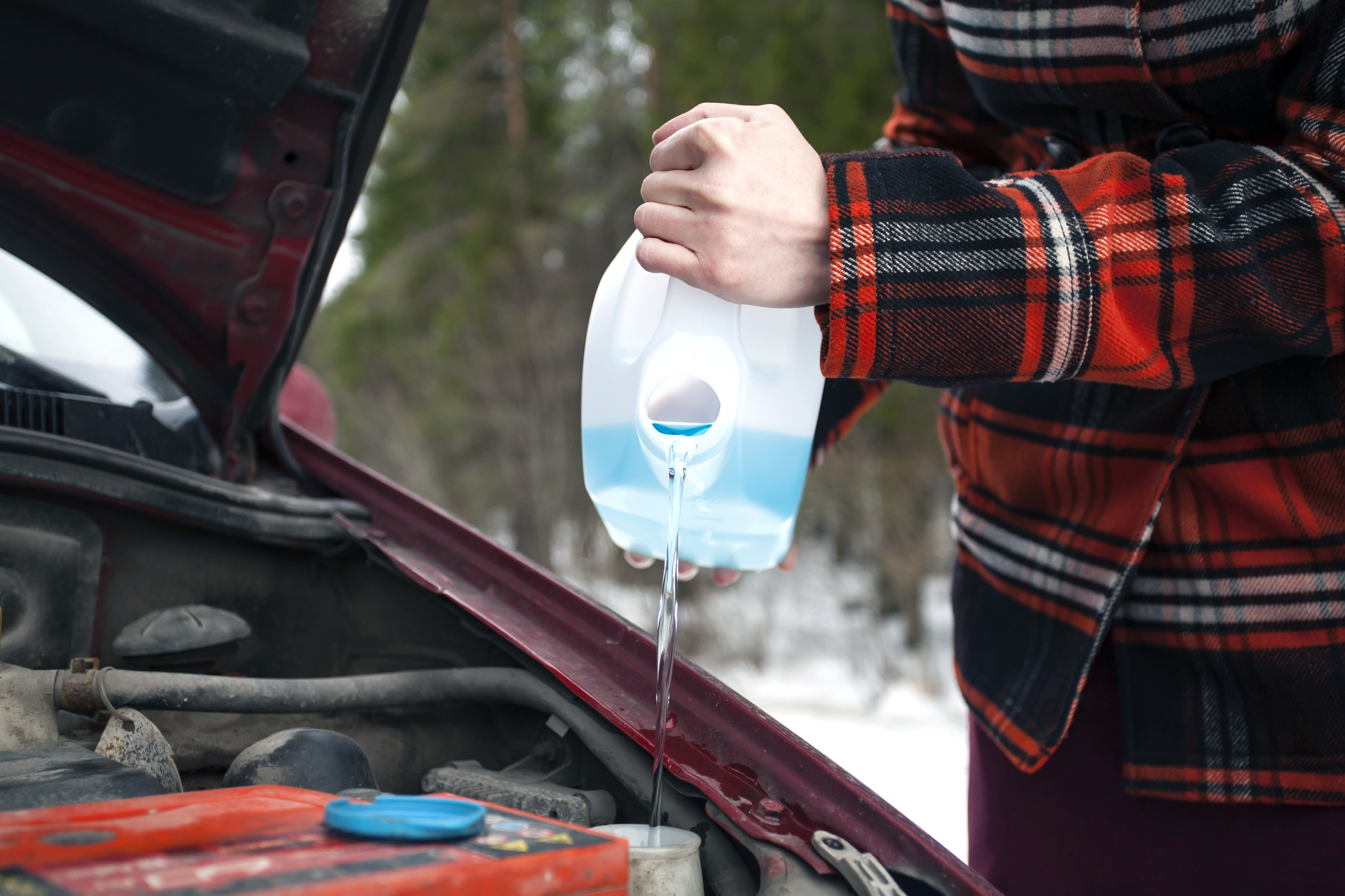 Pouring Antifreeze Washer Fluid into Windshield Washer Tank
