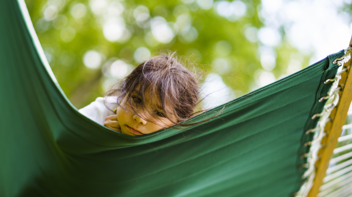 The little 5-years-old girl resting and have fun in the hammock in the park
