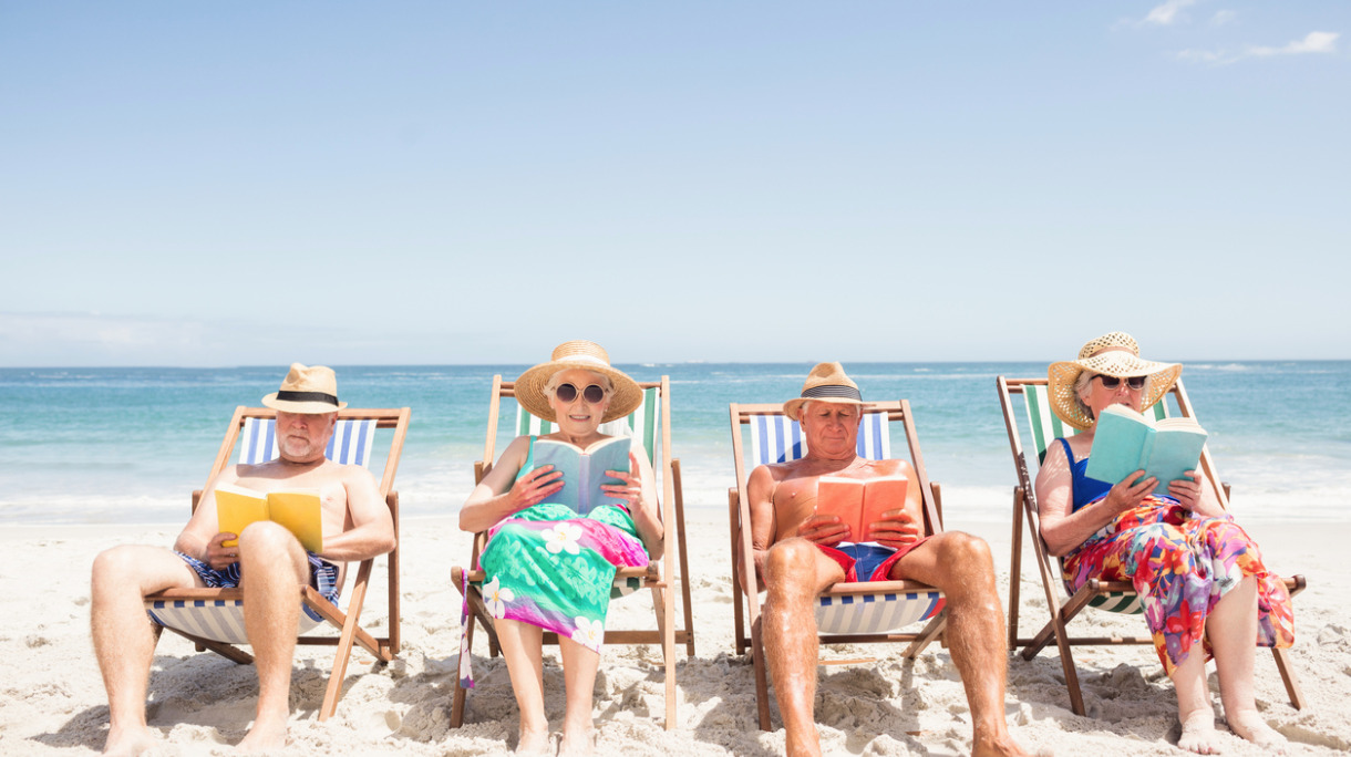 senior-friends-reading-books-on-beach-chair-picture-id698265074