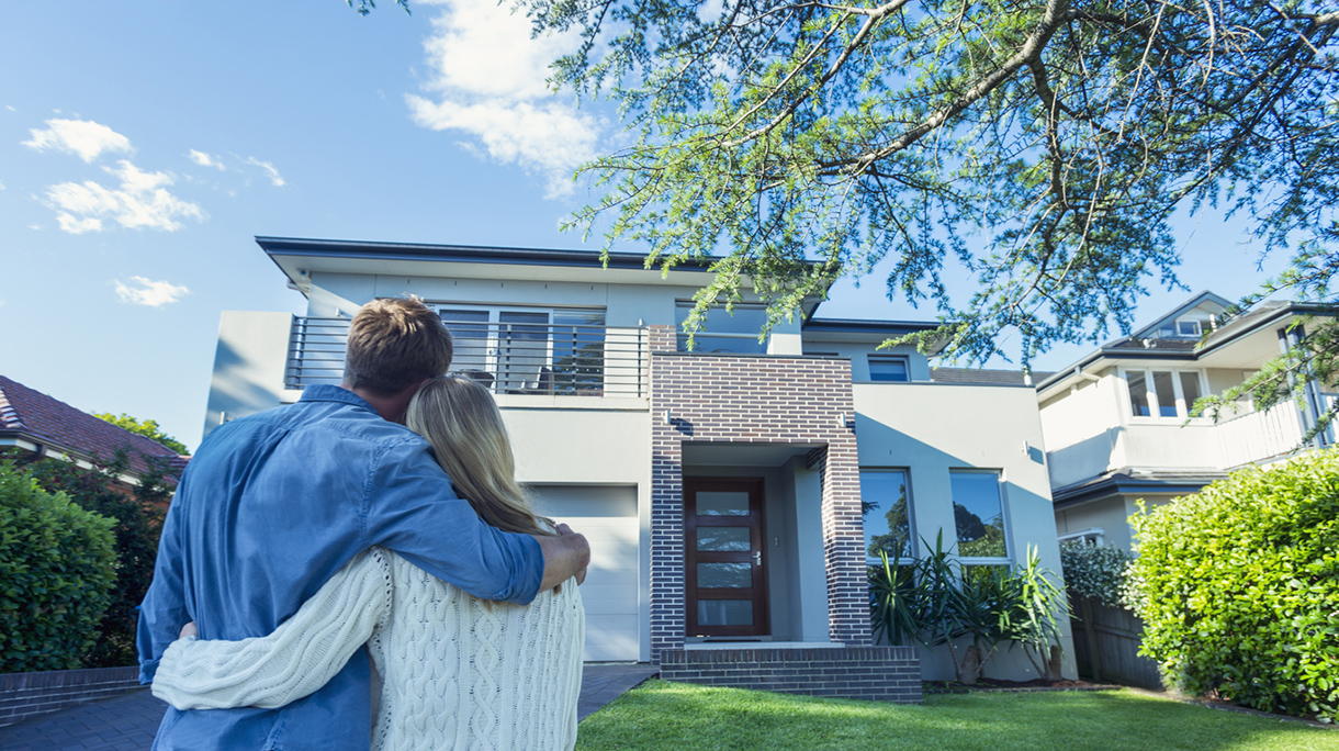 Couple standing in front of their new home.