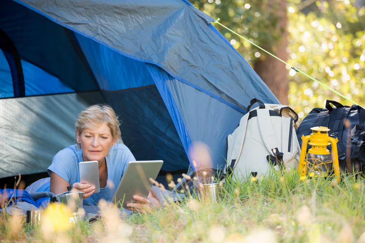 Mature woman looking her smartphone and holding a tablet