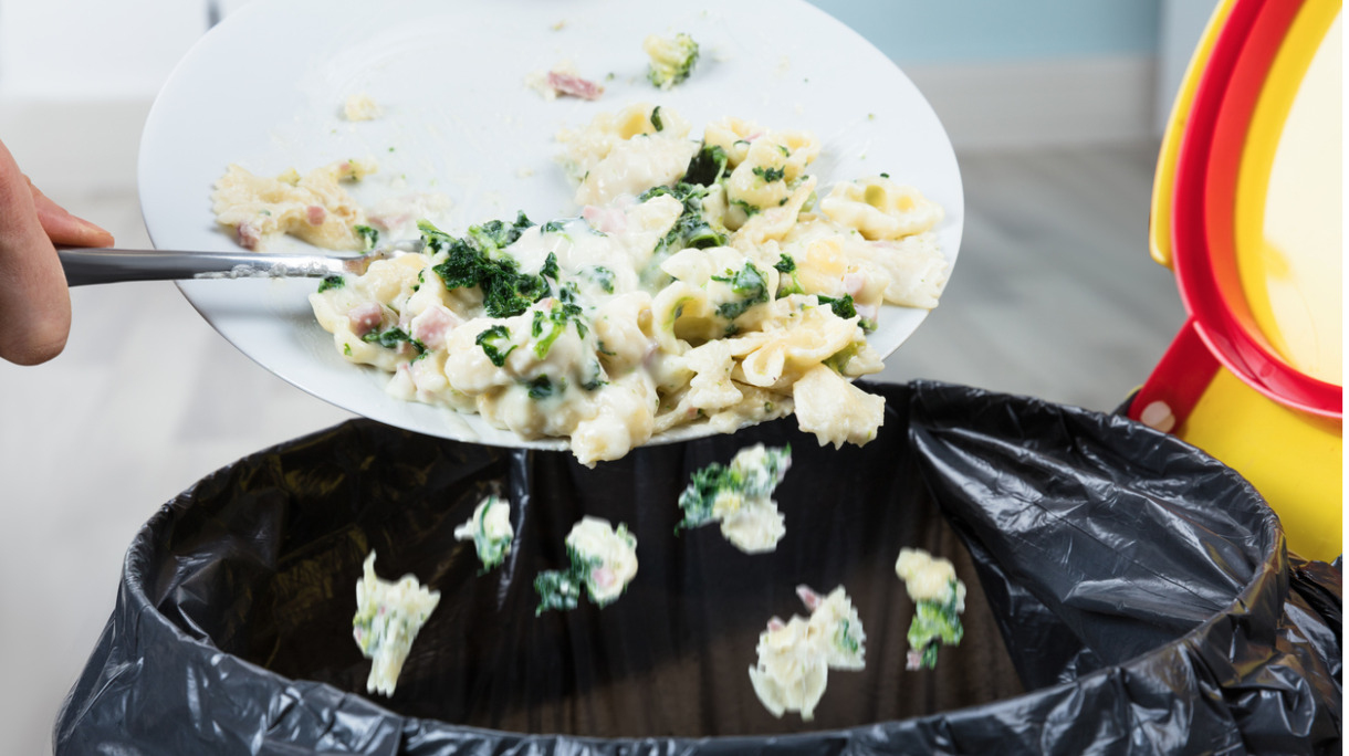 person-throwing-cooked-pasta-in-trash-bin-picture-id8587659241
