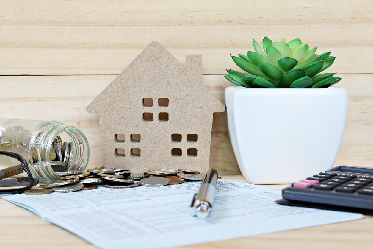 Wood house mode, coins scattered from glass jar, calculator on saving account passbook or financial statement
