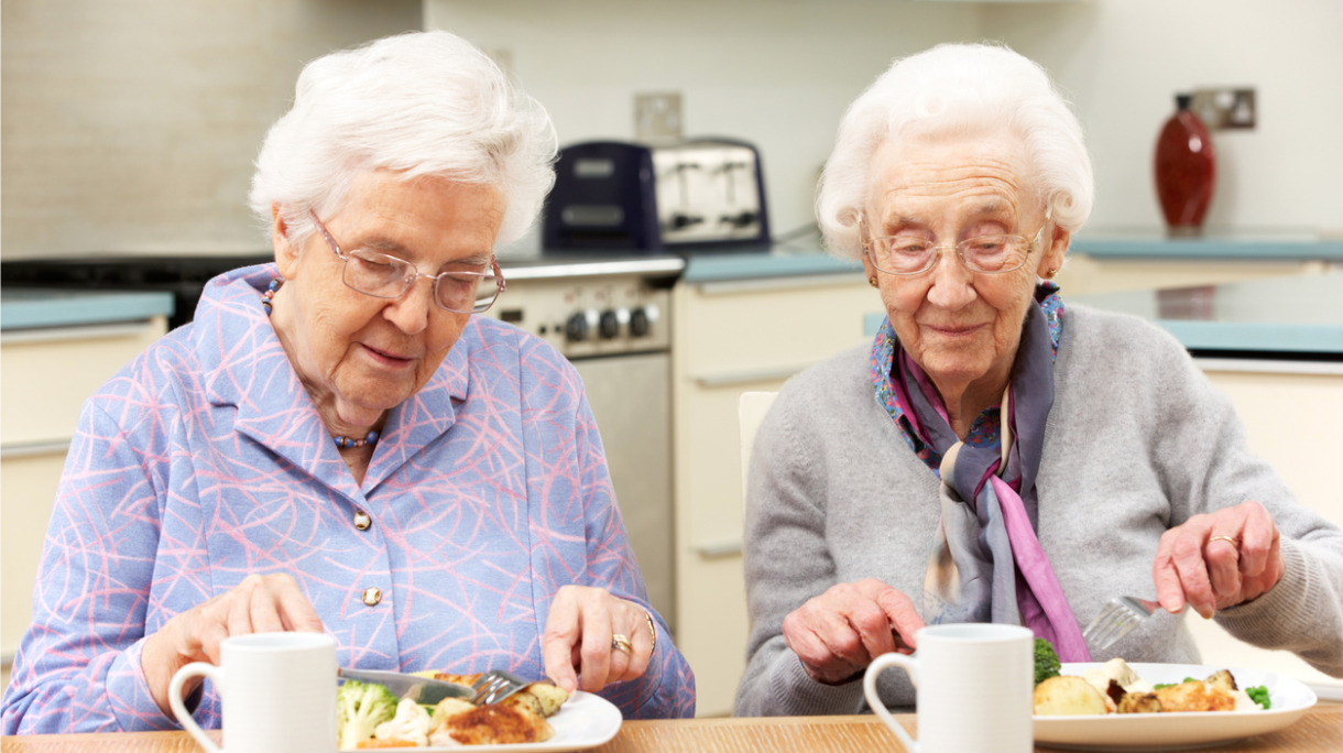 senior-friends-enjoying-meal-in-kitchen-picture-id176988779
