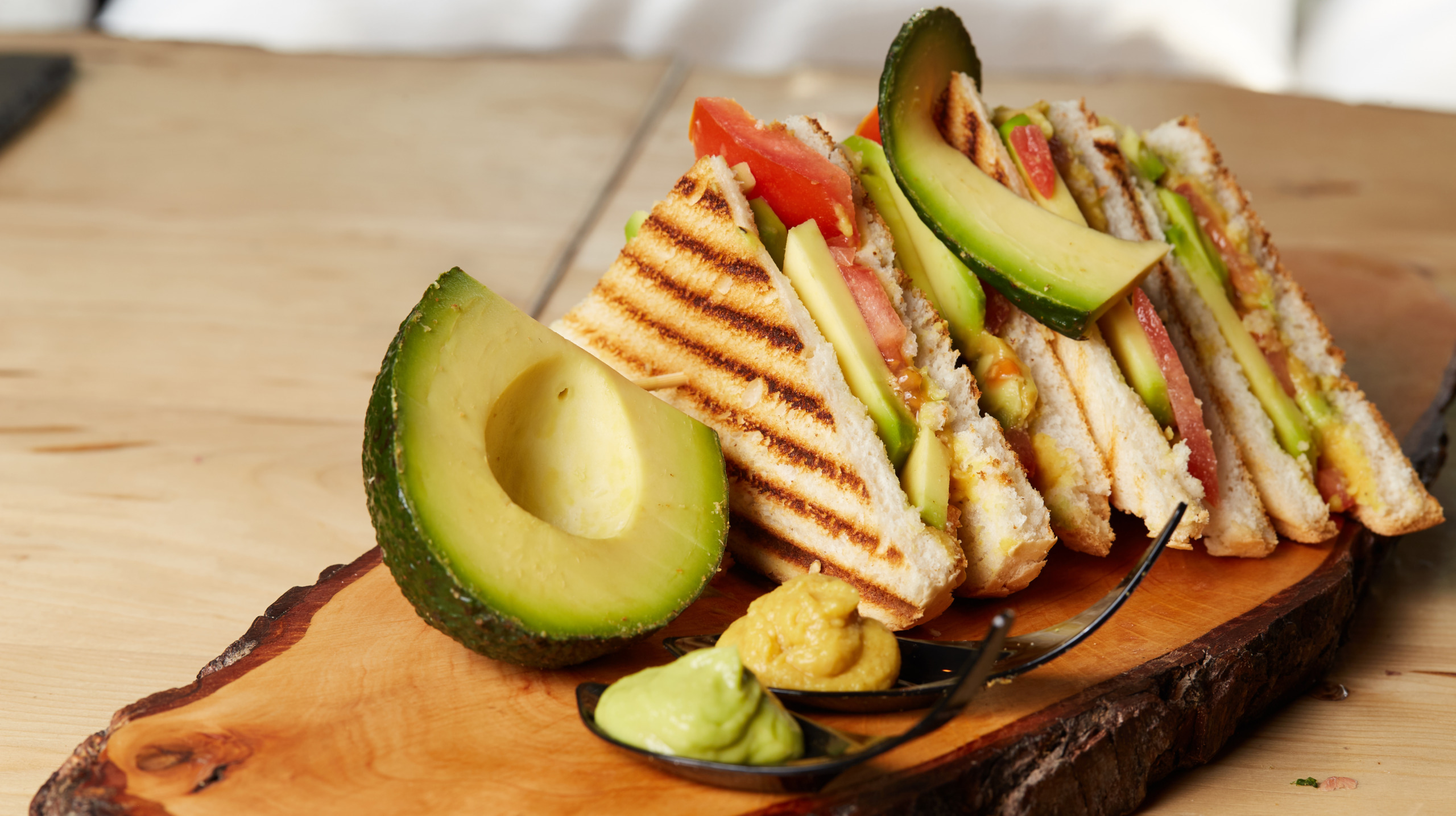 Vegan Club Sandwich with avocado on wooden tray