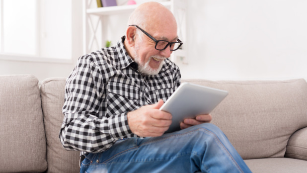 Senior man reading news on digital tablet