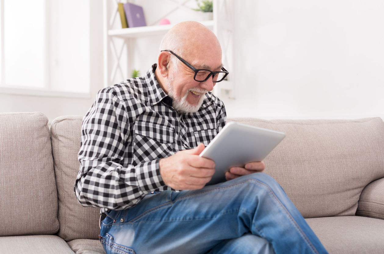 Senior man reading news on digital tablet