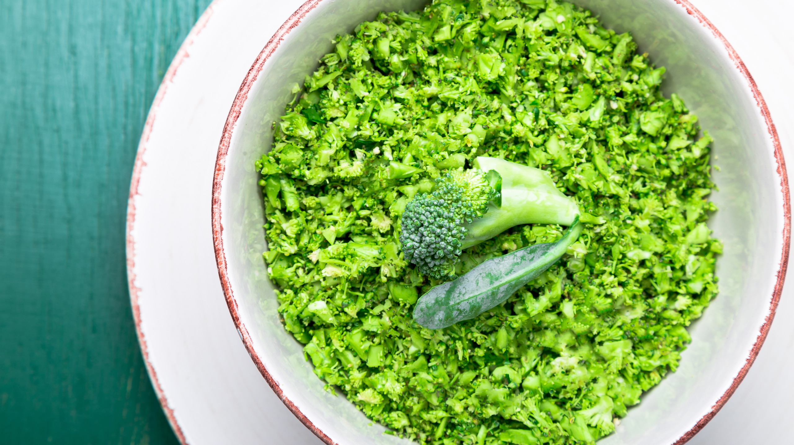 Broccoli rice in bowl on green background. Top view. Overhead. Copy space. Shredded broccoli.