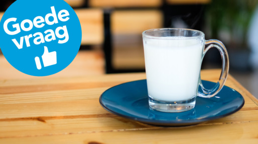Homemade hot fresh milk in clear glass with blue saucer (bottom plate) serve on wooden table, for beverage background or texture – healthy diet concept.