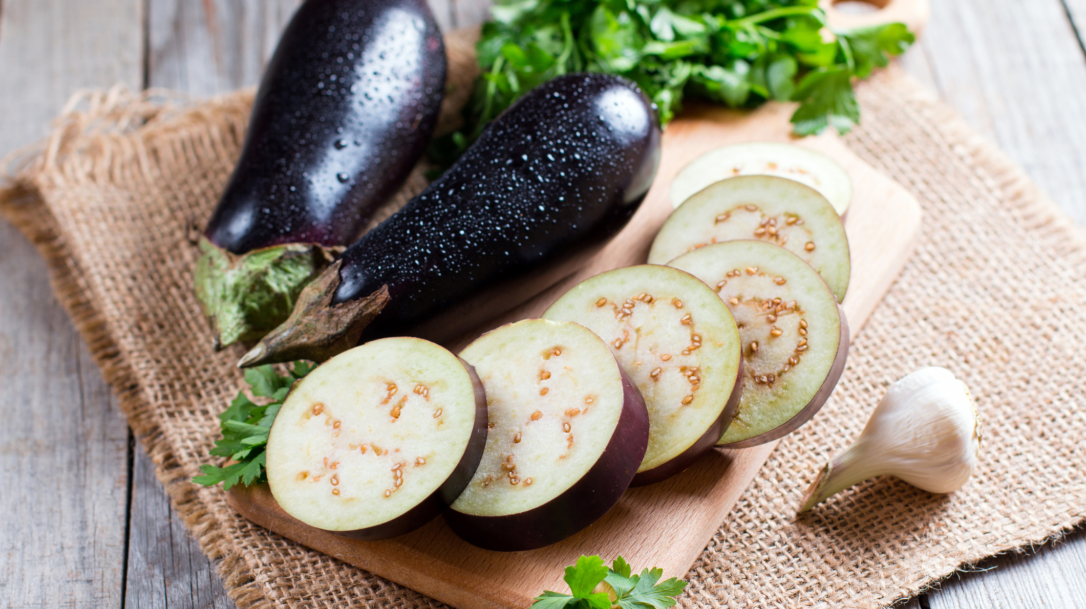 Eggplant slices on cutting board on wooden background