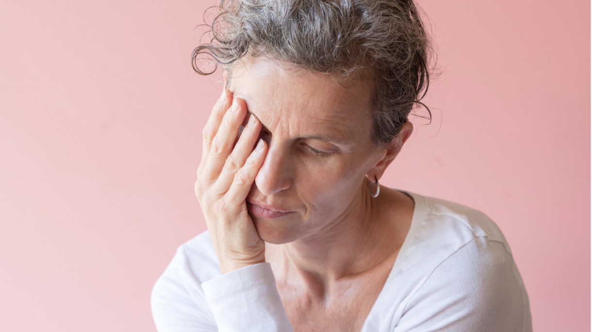 middle-aged-woman-with-hand-over-eye-against-pink-background-picture-id958999526