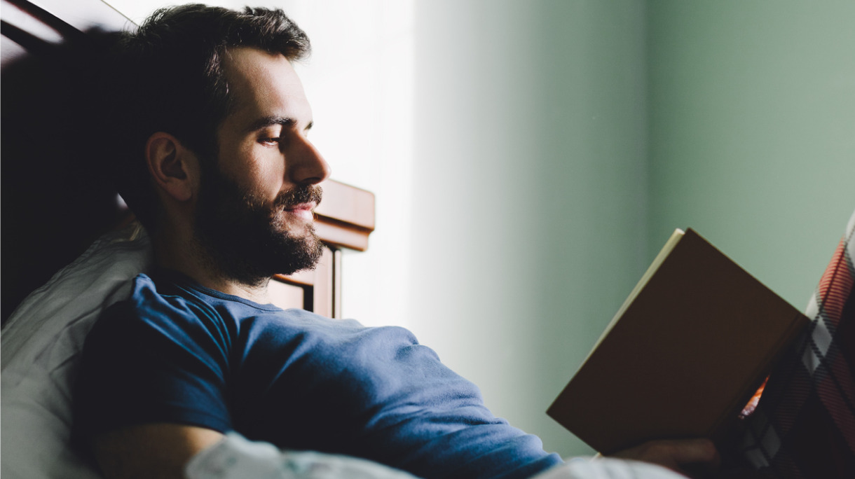 young-man-reading-a-book-in-his-bedroom-picture-id638759726