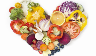 Flat lay conceptual vegan food in heart shape on white background.
