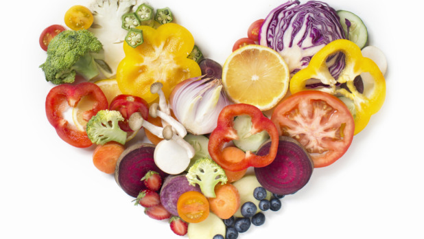 Flat lay conceptual vegan food in heart shape on white background.