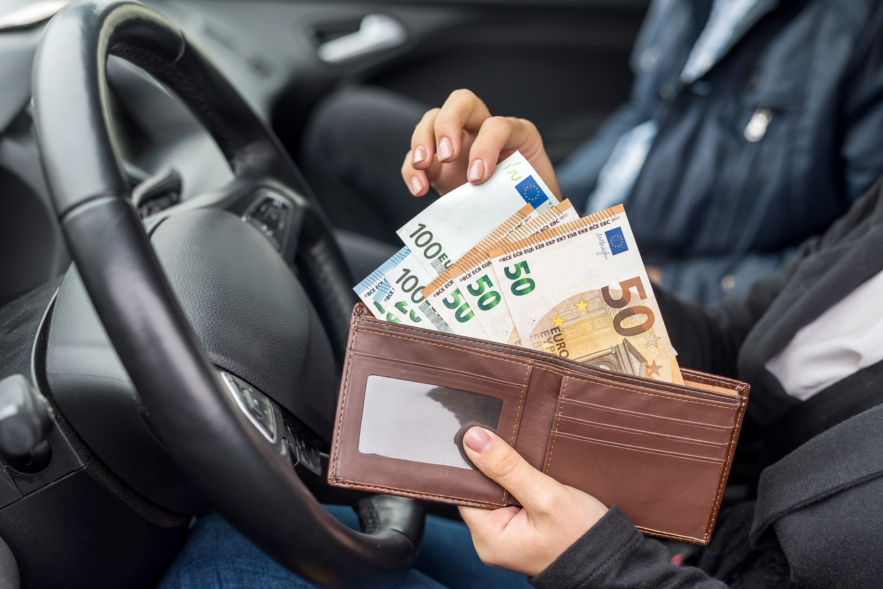 Woman holding wallet with euro sitting in car