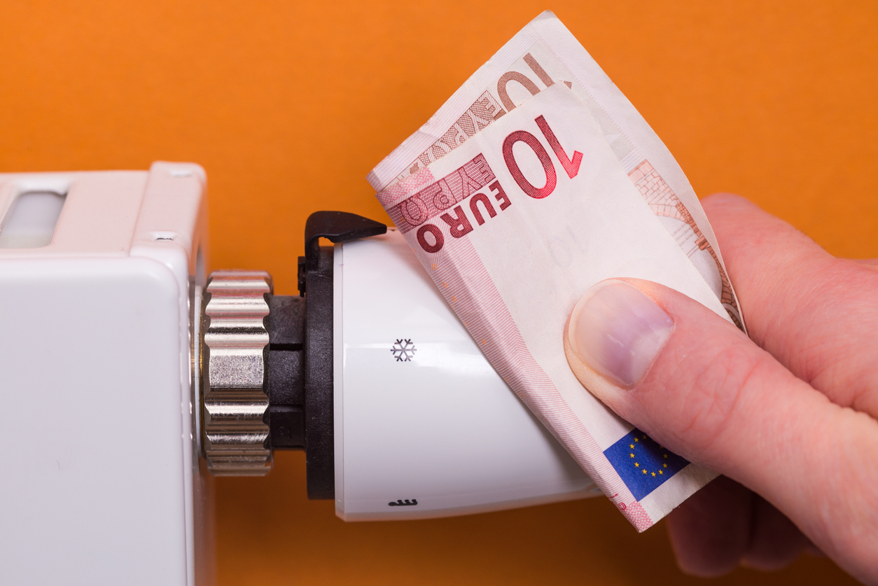 Radiator thermostat, banknote and hand – brown