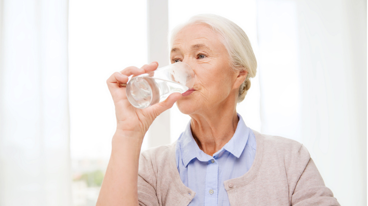 happy-senior-woman-with-glass-of-water-at-home-picture-id621393856
