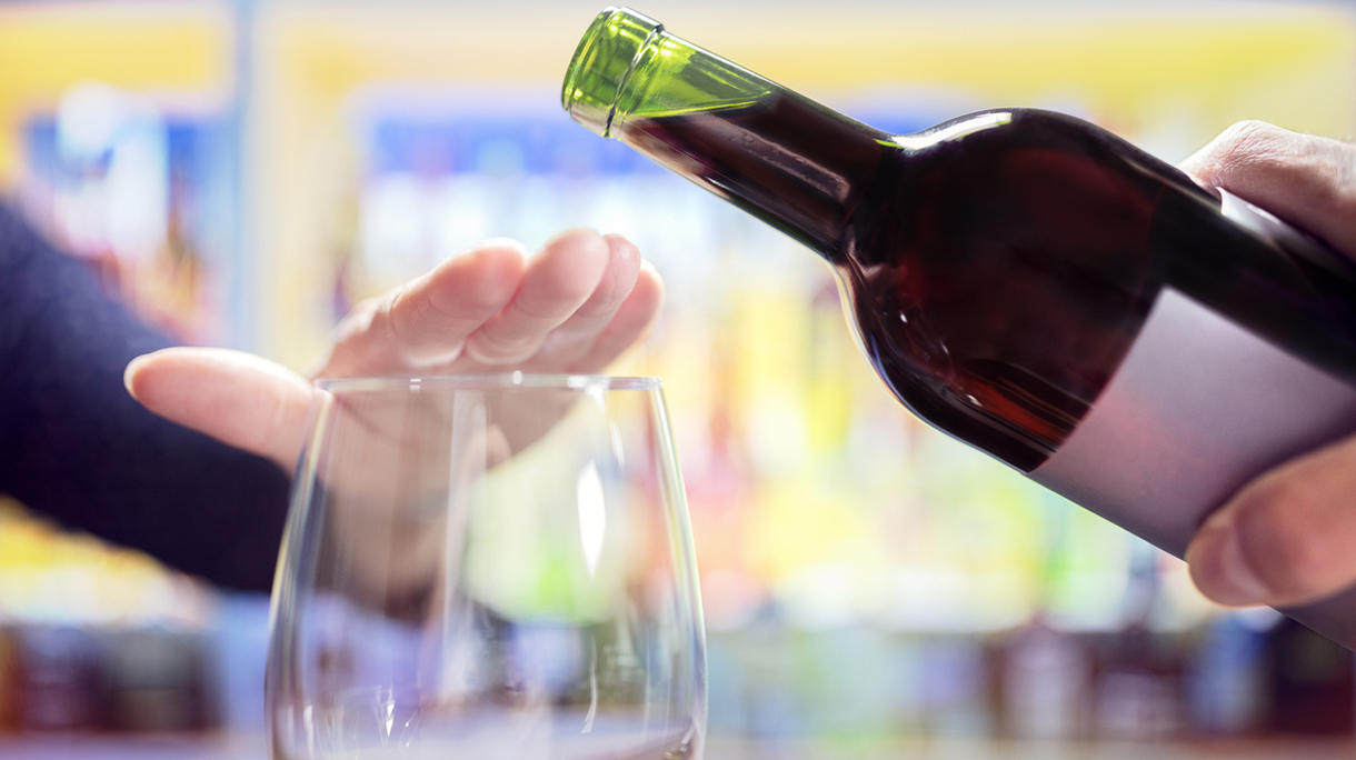 Woman rejecting more alcohol from wine bottle in bar