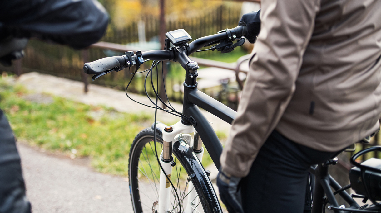 A midsection of active senior couple with electrobikes cycling outdoors.