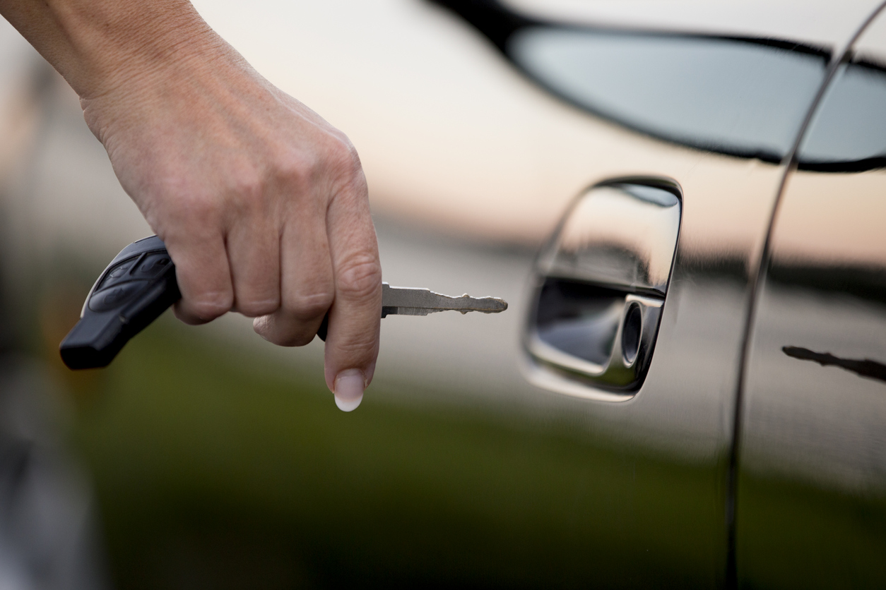 Hand with car key unlock car door