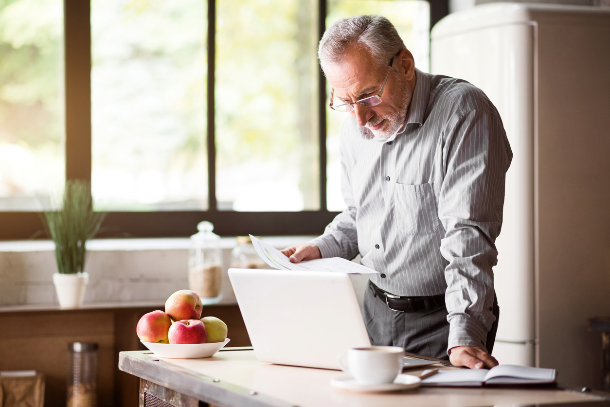 Senior man checking his papers in kitchen at home