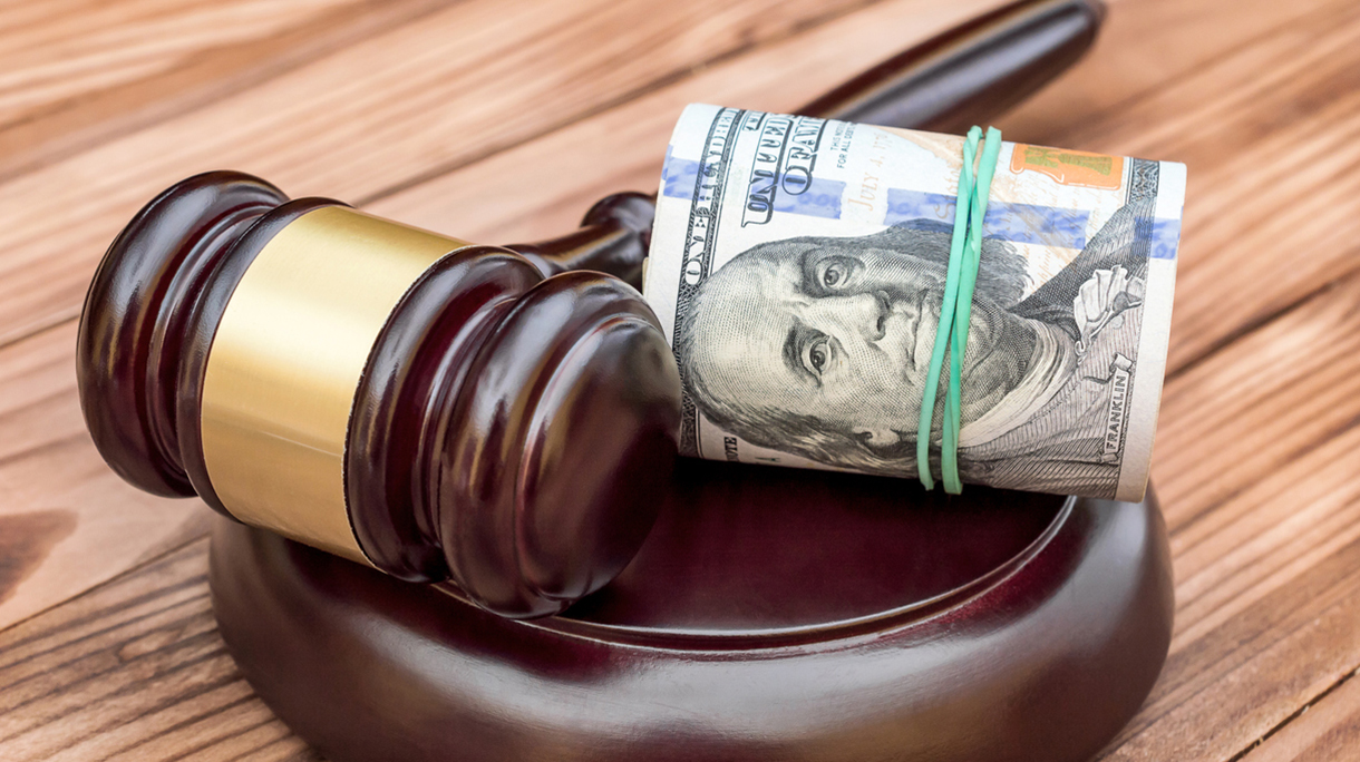 Judge’s gavel with rolled dollar bills on the table.