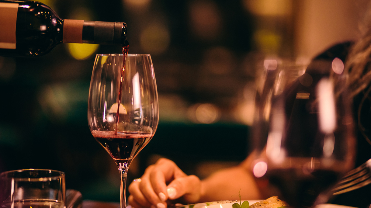 Close-up of sommelier serving red wine at fine dining restaurant