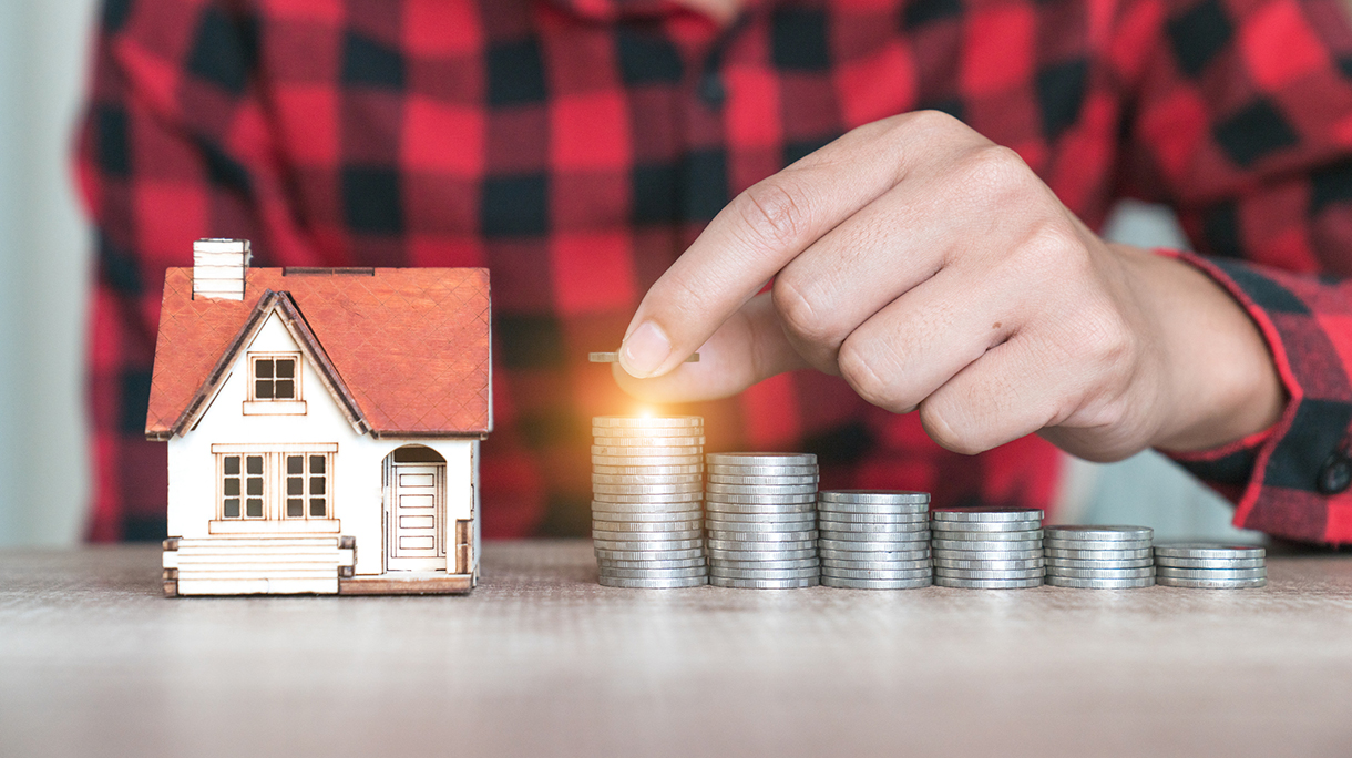 hand putting coin with house model background, gold coins stack on wooden table in the morning sunlight. business, investment, retirement, finance and Money Saving for the future concepts