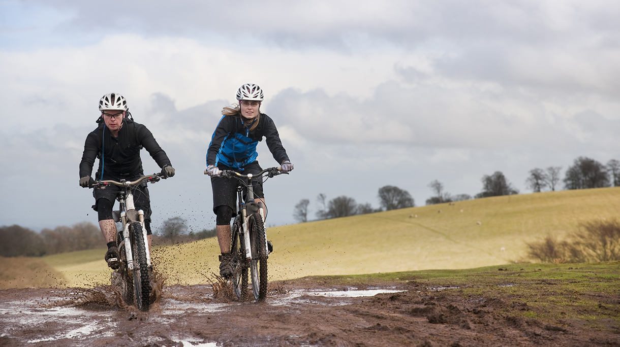 Couple riding bike through muddy puddles