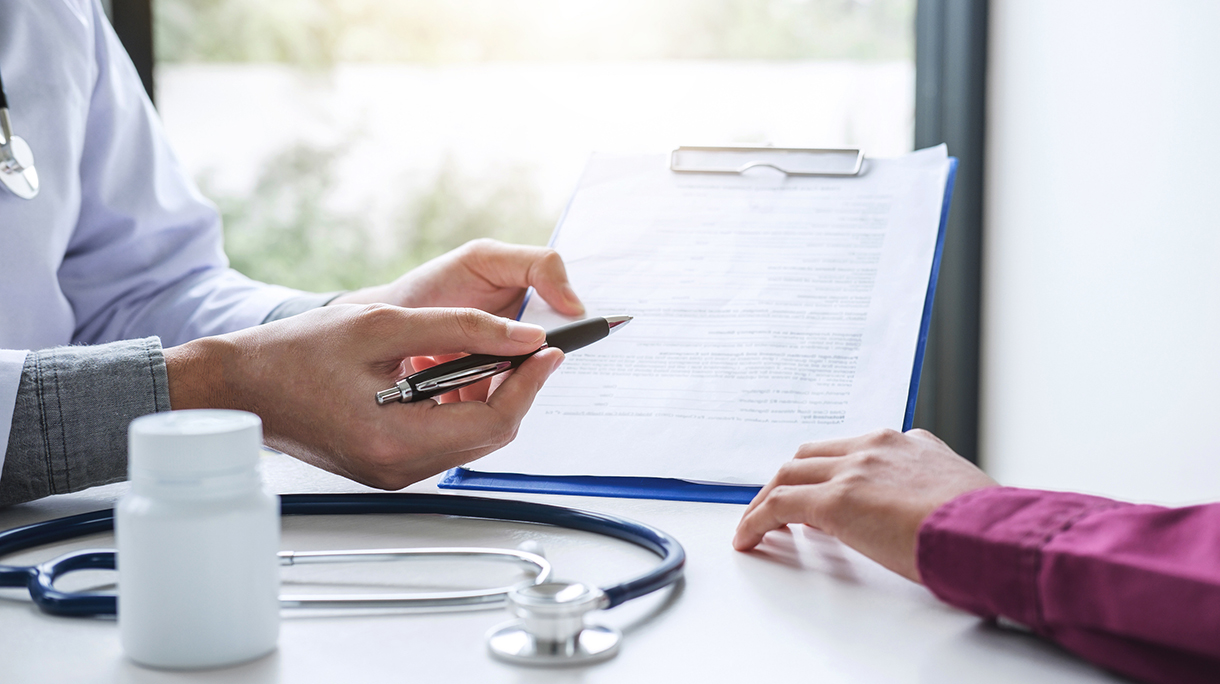 Midsection Of Doctor Showing Insurance Form To Patient