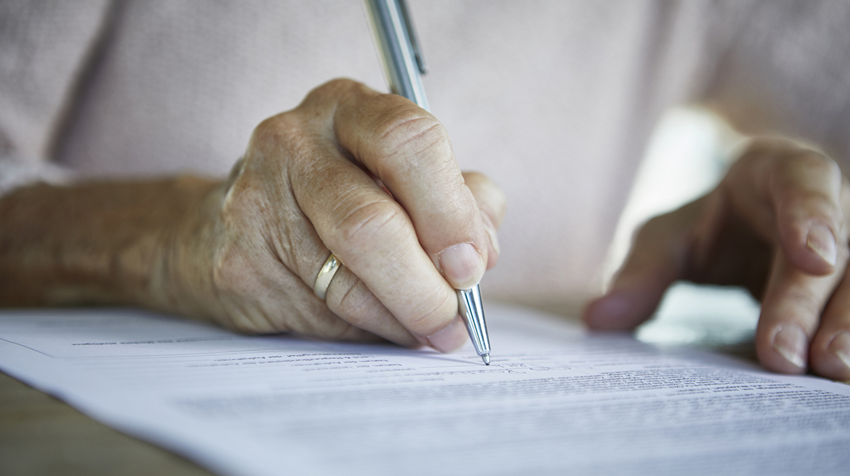 Senior woman’s hand signing a document, close-up