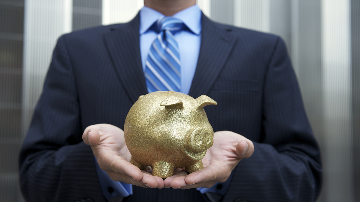Businessman Holding a Golden Piggy Bank Outdoors