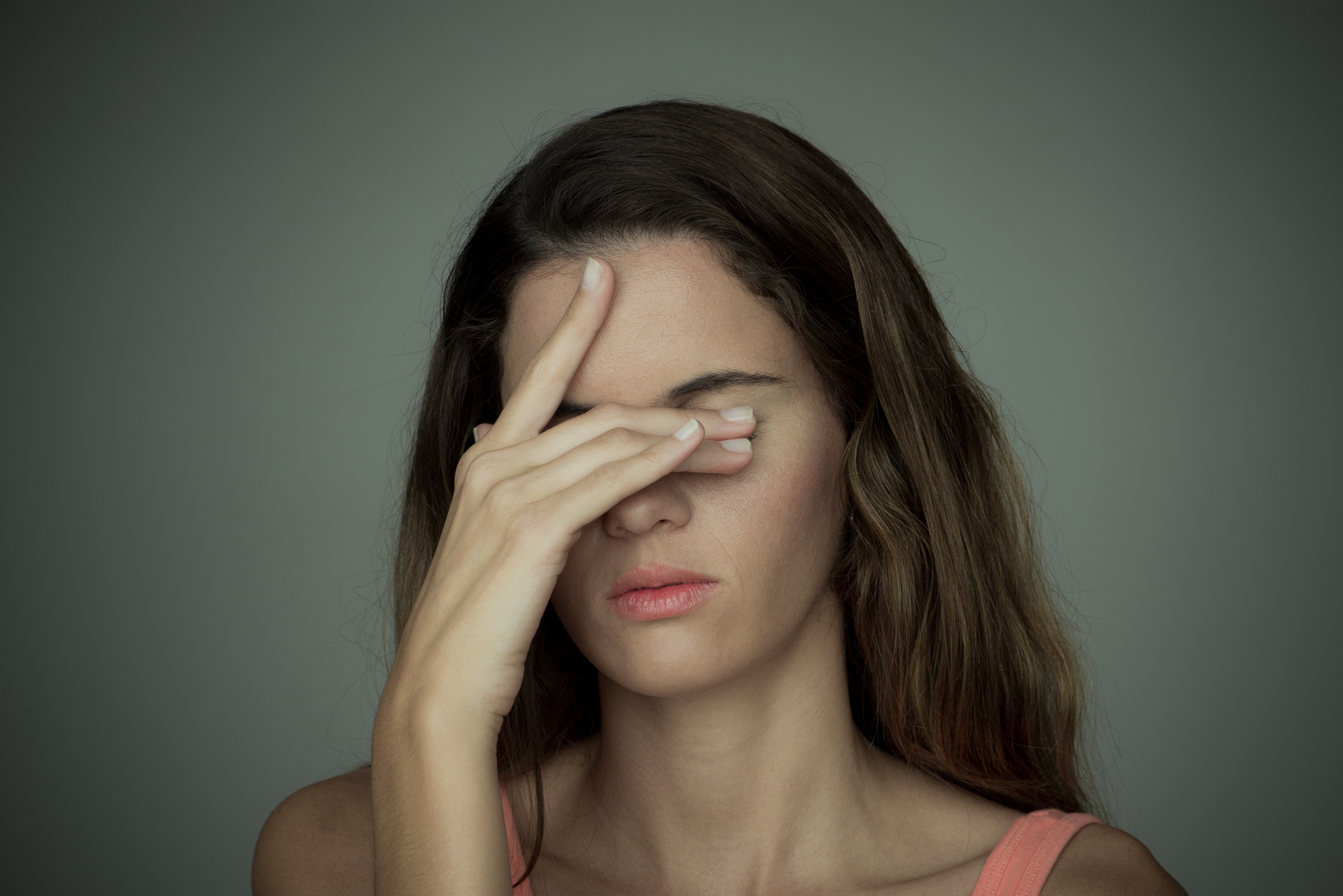 Young woman covering her eyes with one hand