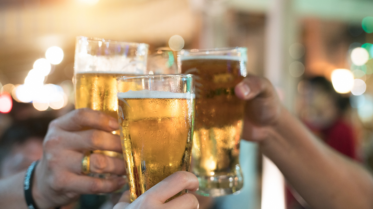Friends toasting with glasses of light beer at the pub. Beautiful background of the Oktoberfest. A group of young people while relaxing at the bar. fine grain. Soft focus. Shallow DOF.