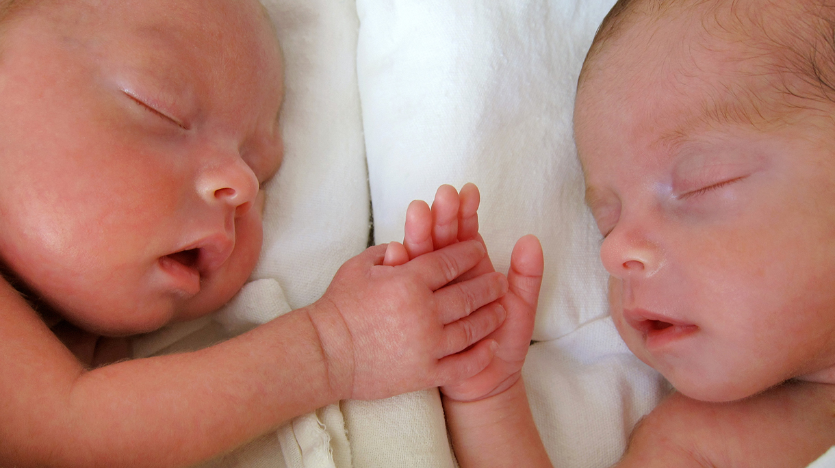 Newborn Premature Twins holding hands