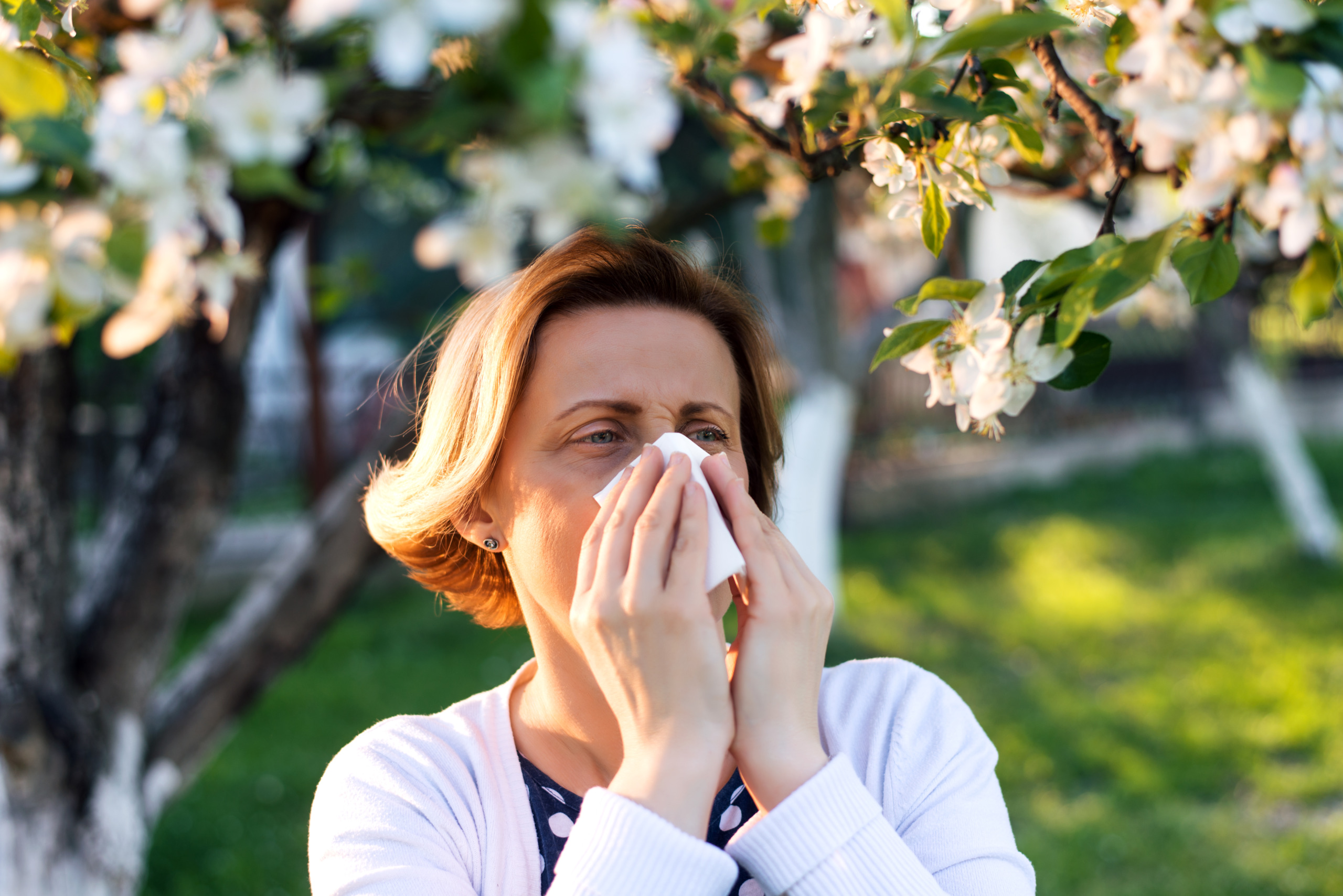 Woman sneezing in the blossoming garden