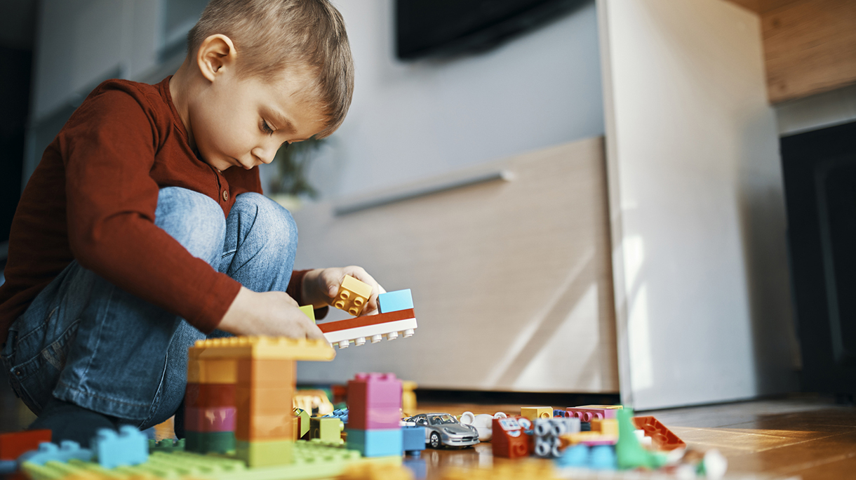 Little boy crouching on the floor at home playing with building bricks