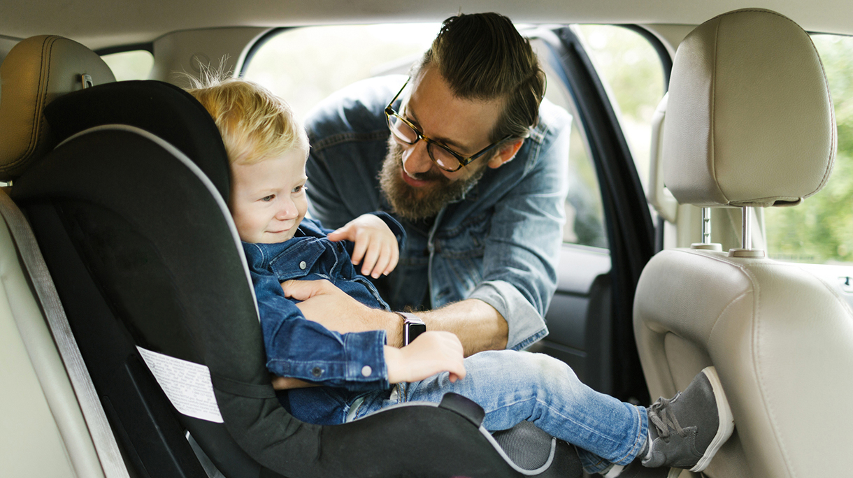 Man putting his son into car seat