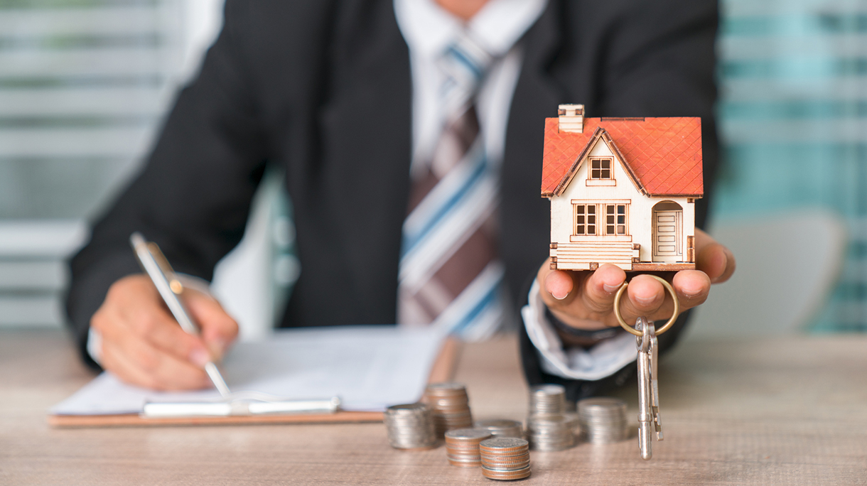 real estate and property concept – close up of hands holding house or home model