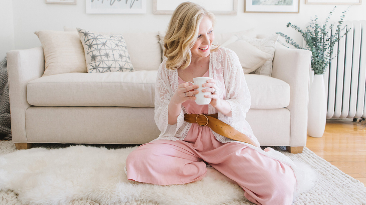 Young woman sitting on living room floor with coffee