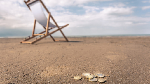 Deck chair on beach, coins on sand in foreground