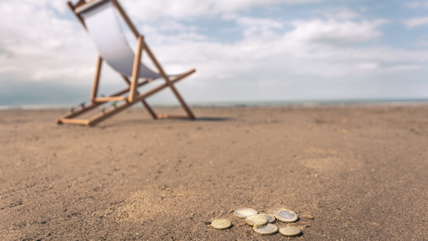 Deck chair on beach, coins on sand in foreground