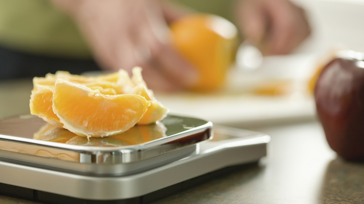 Senior woman weighing orange on scale