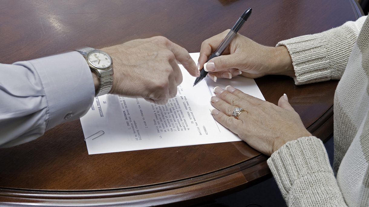 Lawyer shows female client where to sign will